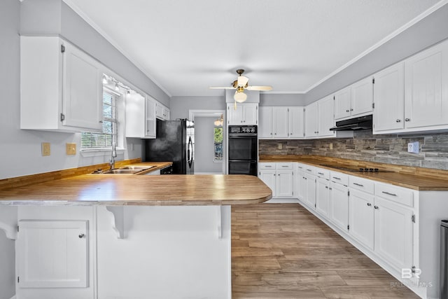 kitchen featuring white cabinets, black appliances, tasteful backsplash, sink, and kitchen peninsula