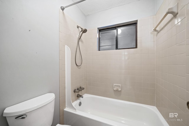 bathroom with a textured ceiling, toilet, and tiled shower / bath combo