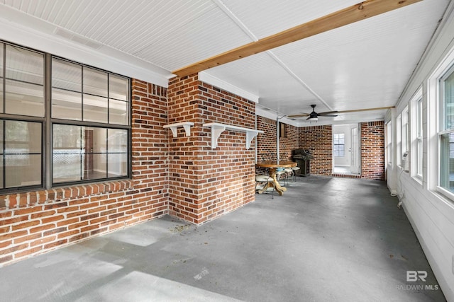 unfurnished sunroom with ceiling fan and a wood stove