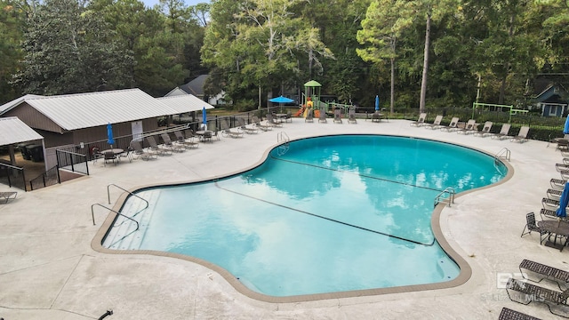 view of swimming pool featuring a playground and a patio