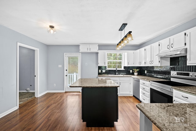 kitchen featuring a kitchen island, appliances with stainless steel finishes, decorative light fixtures, white cabinets, and light stone countertops