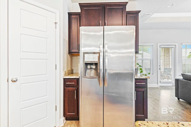 kitchen with light wood-type flooring, stainless steel fridge, and light stone countertops