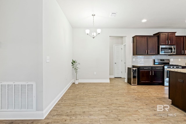 kitchen with a chandelier, decorative light fixtures, decorative backsplash, appliances with stainless steel finishes, and light hardwood / wood-style floors