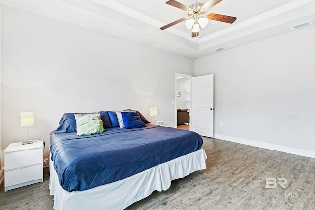 bedroom with ceiling fan, hardwood / wood-style flooring, and a raised ceiling