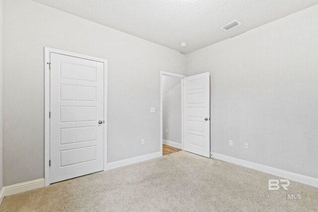 unfurnished bedroom with a textured ceiling and light colored carpet