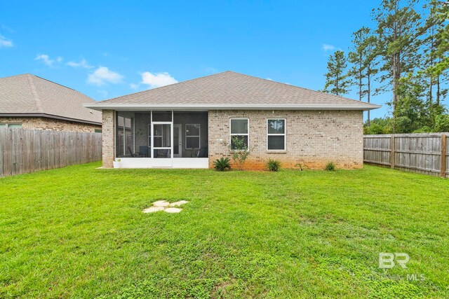 rear view of house featuring a sunroom and a yard