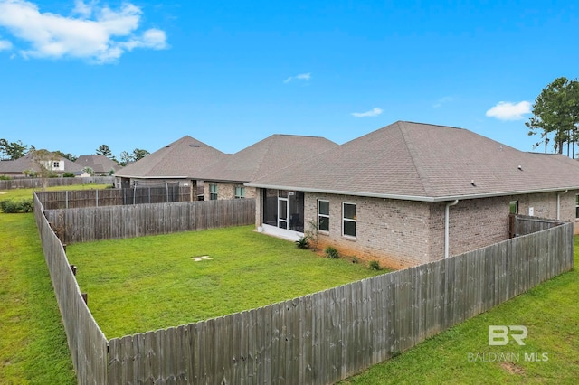 rear view of house with a sunroom and a yard