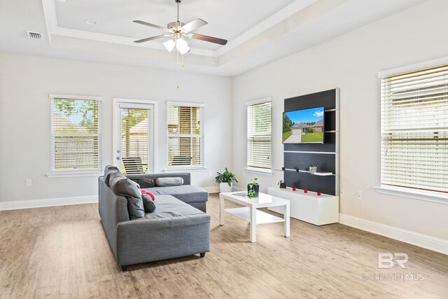 living room with ceiling fan, a tray ceiling, and light hardwood / wood-style floors