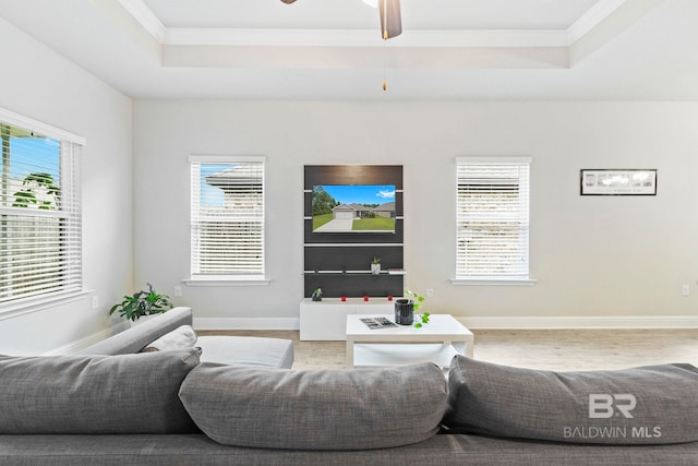 living room with crown molding, a raised ceiling, wood-type flooring, and ceiling fan