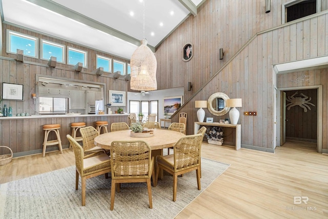 dining space with light hardwood / wood-style flooring, plenty of natural light, high vaulted ceiling, and beamed ceiling