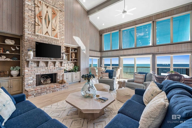 living room featuring light hardwood / wood-style flooring, built in features, high vaulted ceiling, a fireplace, and wood walls