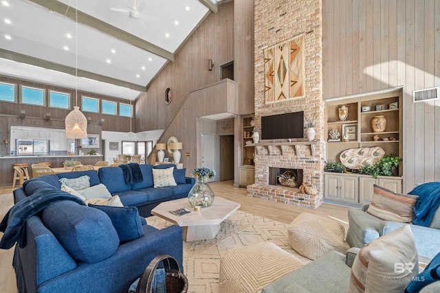 living room with a fireplace, beam ceiling, wooden walls, and high vaulted ceiling