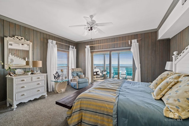 carpeted bedroom featuring access to exterior, wooden walls, ornamental molding, and ceiling fan