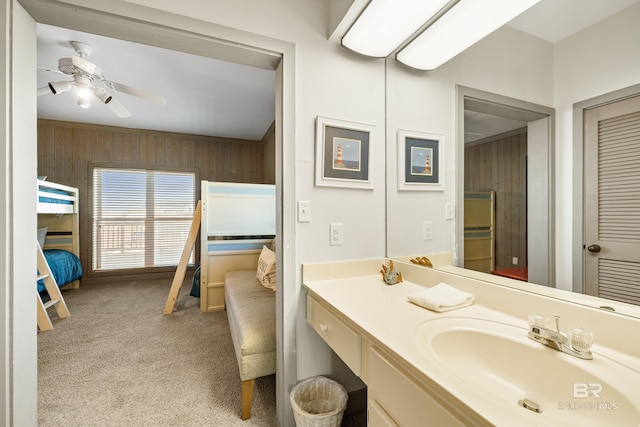 bathroom featuring ceiling fan, vanity, and wooden walls