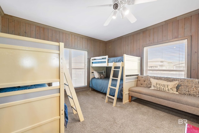 carpeted bedroom featuring crown molding, ceiling fan, and wood walls