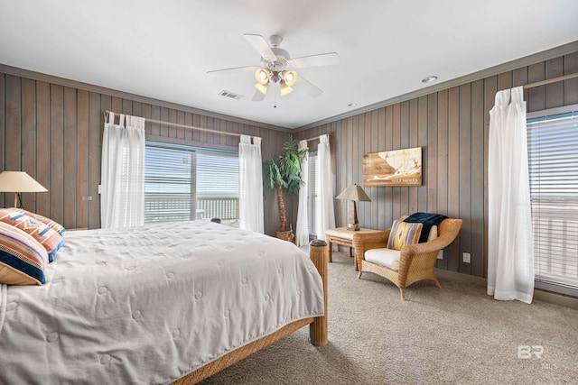 bedroom featuring ceiling fan, carpet, and wooden walls