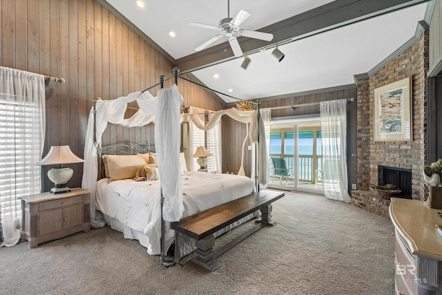 carpeted bedroom with access to exterior, a fireplace, lofted ceiling with beams, and wood walls