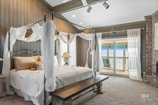 carpeted bedroom featuring access to exterior, wooden walls, a water view, lofted ceiling with beams, and a brick fireplace