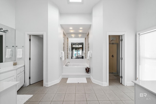 bathroom featuring tile patterned flooring, vanity, a tub, and a towering ceiling