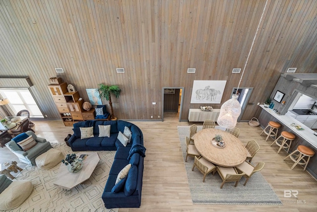 living room featuring wood walls, light wood-type flooring, and a high ceiling
