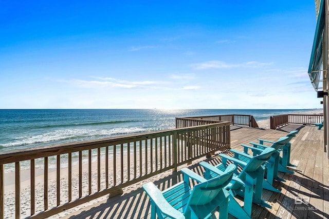 wooden deck featuring a beach view and a water view