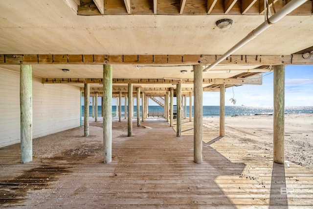 wooden terrace featuring a view of the beach and a water view