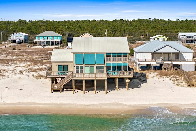 rear view of house featuring a water view and a beach view