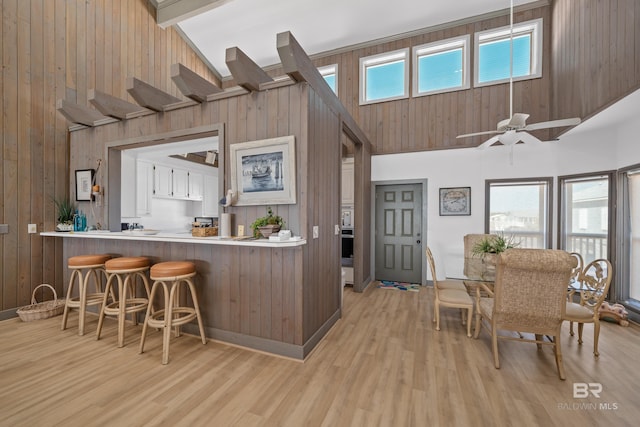 interior space featuring high vaulted ceiling, a healthy amount of sunlight, a kitchen bar, and light hardwood / wood-style floors