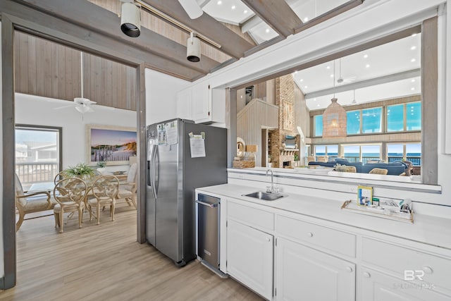 kitchen with white cabinetry, sink, beam ceiling, and stainless steel appliances