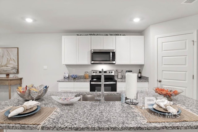 kitchen featuring white cabinetry, recessed lighting, light stone countertops, and appliances with stainless steel finishes