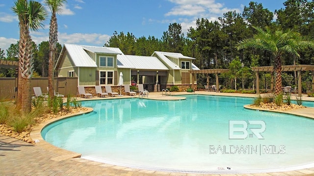 pool with a pergola, a patio, and fence