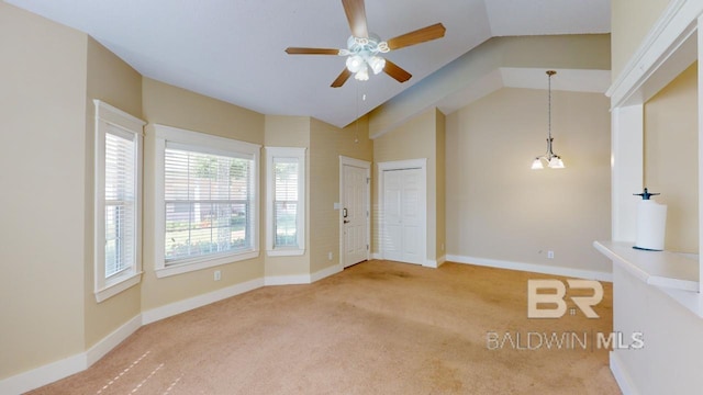 spare room with lofted ceiling, ceiling fan with notable chandelier, and carpet