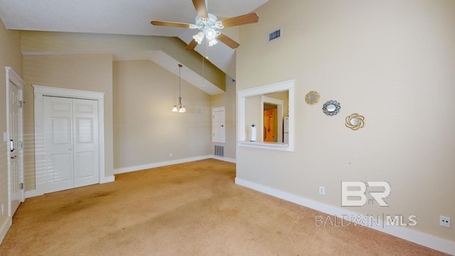 unfurnished living room with high vaulted ceiling, ceiling fan with notable chandelier, and carpet