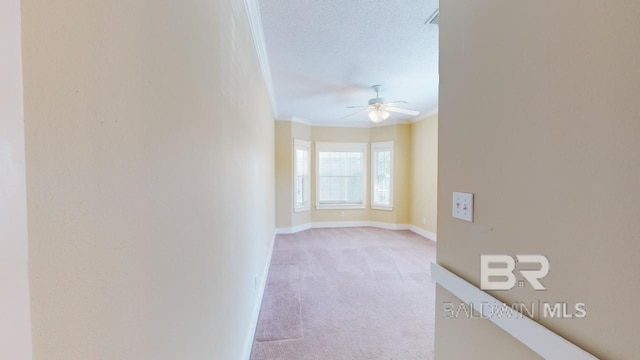 carpeted empty room with a textured ceiling, ceiling fan, and crown molding