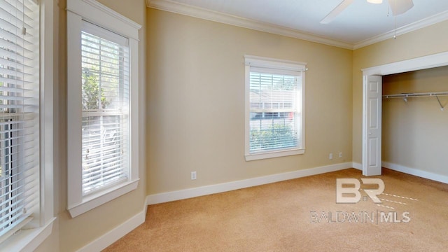 unfurnished bedroom with ceiling fan, light colored carpet, ornamental molding, and a closet