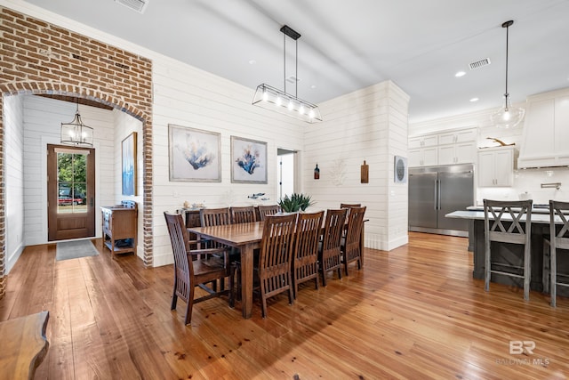 dining area featuring light wood-style floors, arched walkways, visible vents, and recessed lighting