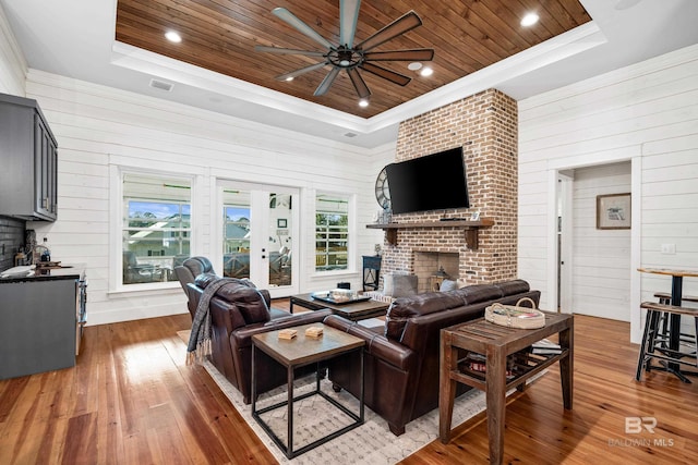 living room featuring wood ceiling, a raised ceiling, and hardwood / wood-style floors