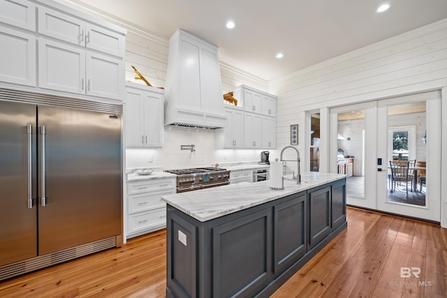 kitchen with white cabinetry, custom range hood, and high quality appliances