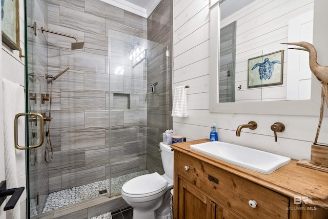 full bath with a stall shower, vanity, toilet, and wooden walls