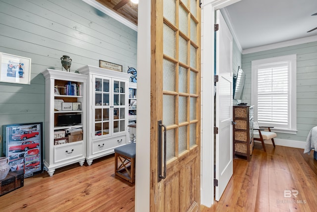 interior space with ornamental molding, wood walls, and hardwood / wood-style flooring