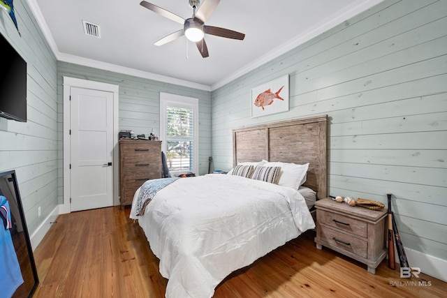 bedroom featuring ornamental molding, visible vents, ceiling fan, and wood finished floors