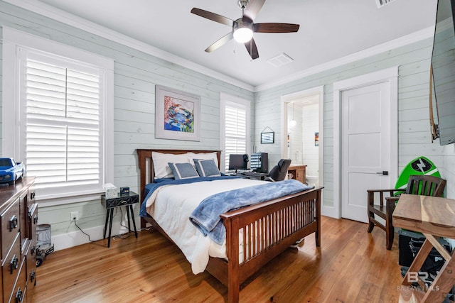 bedroom with light wood-style flooring, crown molding, visible vents, and a ceiling fan