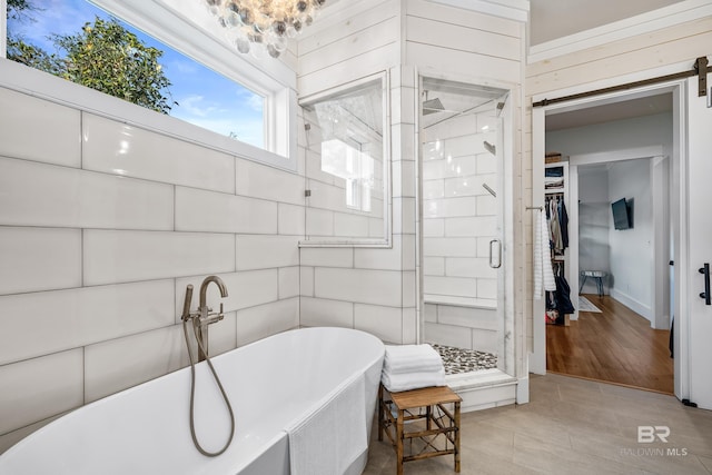 full bath with a freestanding bath, a spacious closet, a stall shower, and tile patterned flooring