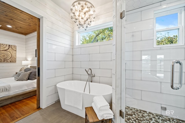 ensuite bathroom featuring a soaking tub, wood walls, and ensuite bathroom