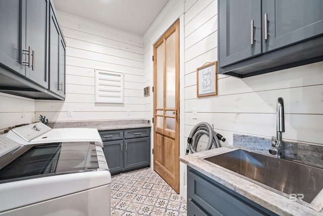 laundry area featuring cabinet space, wood walls, a sink, and independent washer and dryer