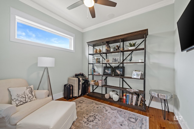 sitting room featuring ornamental molding, wood finished floors, a ceiling fan, and baseboards