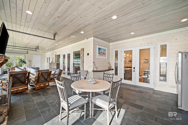 interior space with wooden ceiling, recessed lighting, wooden walls, french doors, and stone finish floor