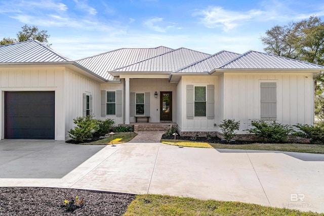 view of front facade featuring a garage, a standing seam roof, driveway, and metal roof