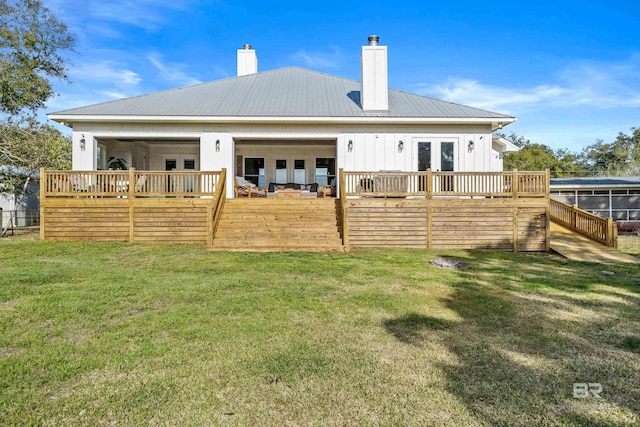 rear view of property with a yard, a wooden deck, metal roof, and french doors