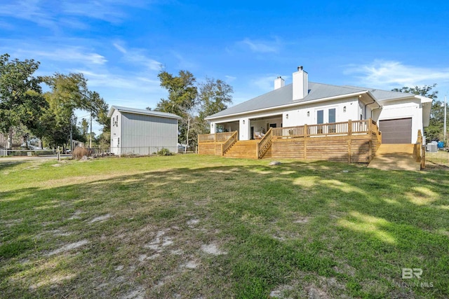 rear view of property with a deck, metal roof, a lawn, and a chimney